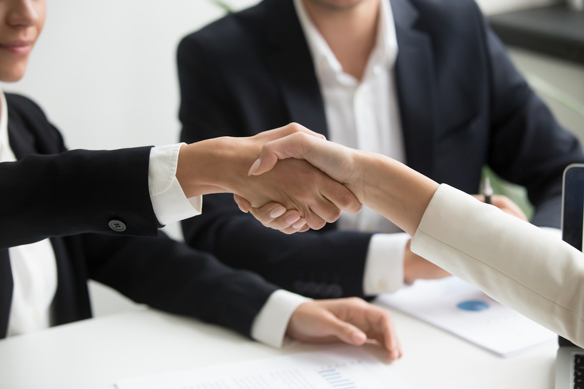 Professionals shaking hands over a laptop